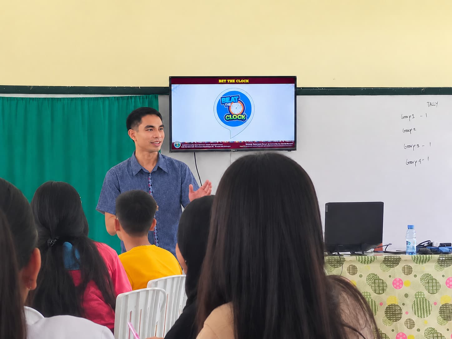 Fil Ilagan teaching a class in his classroom, students seated facing the screen.